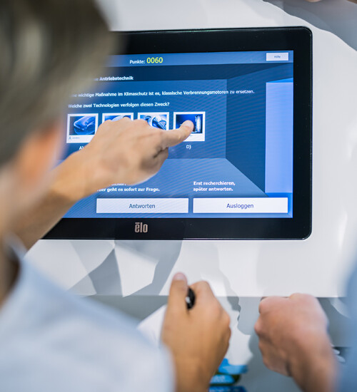 Nahaufnahme einer Hand bei Bedienung einer Sation des Klima-Quiz in der Ausstellung.